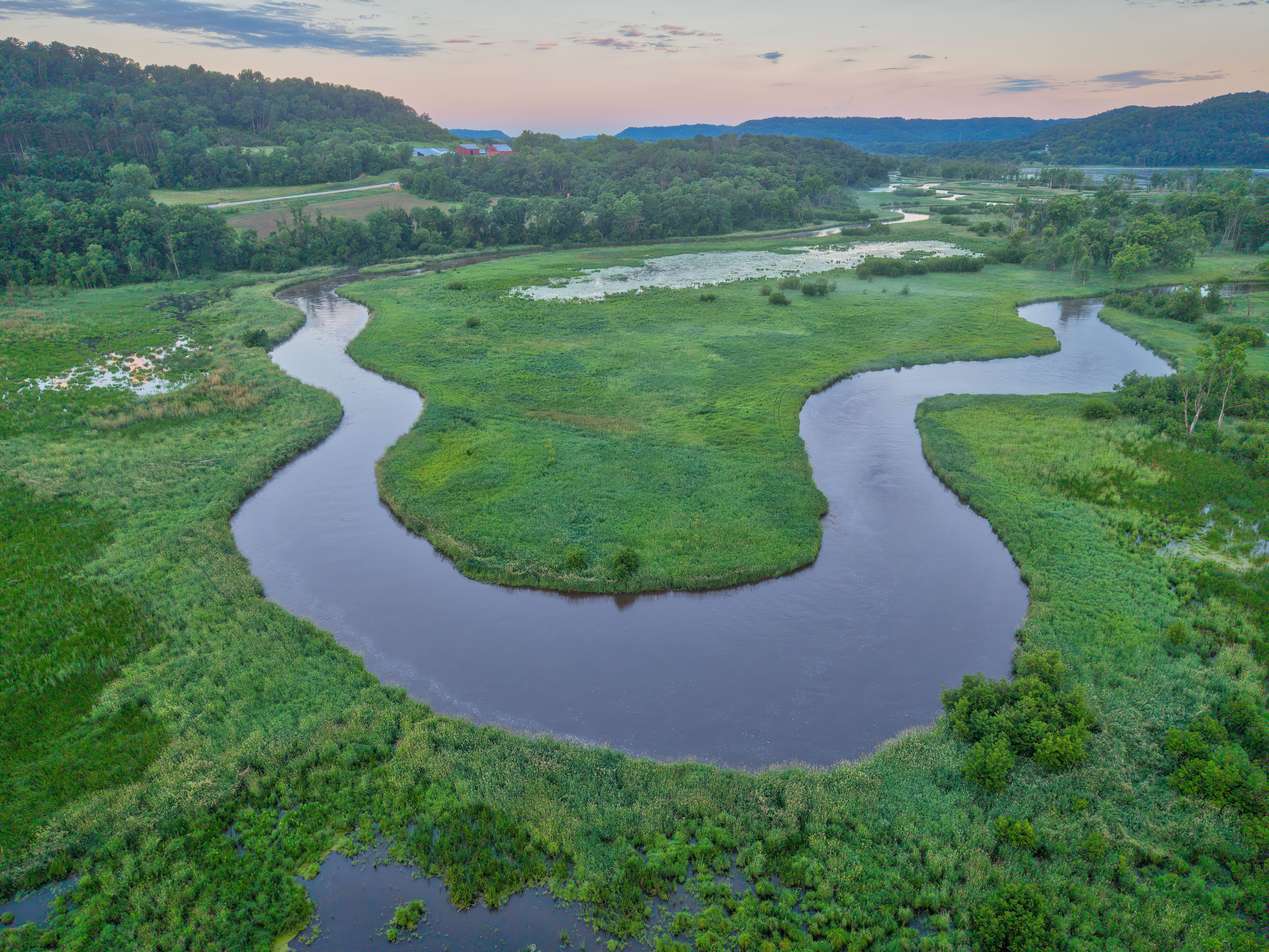 Aerial view of a winding river surrounded by greenery, a sensitive habitat that environmental projects may need to protect.