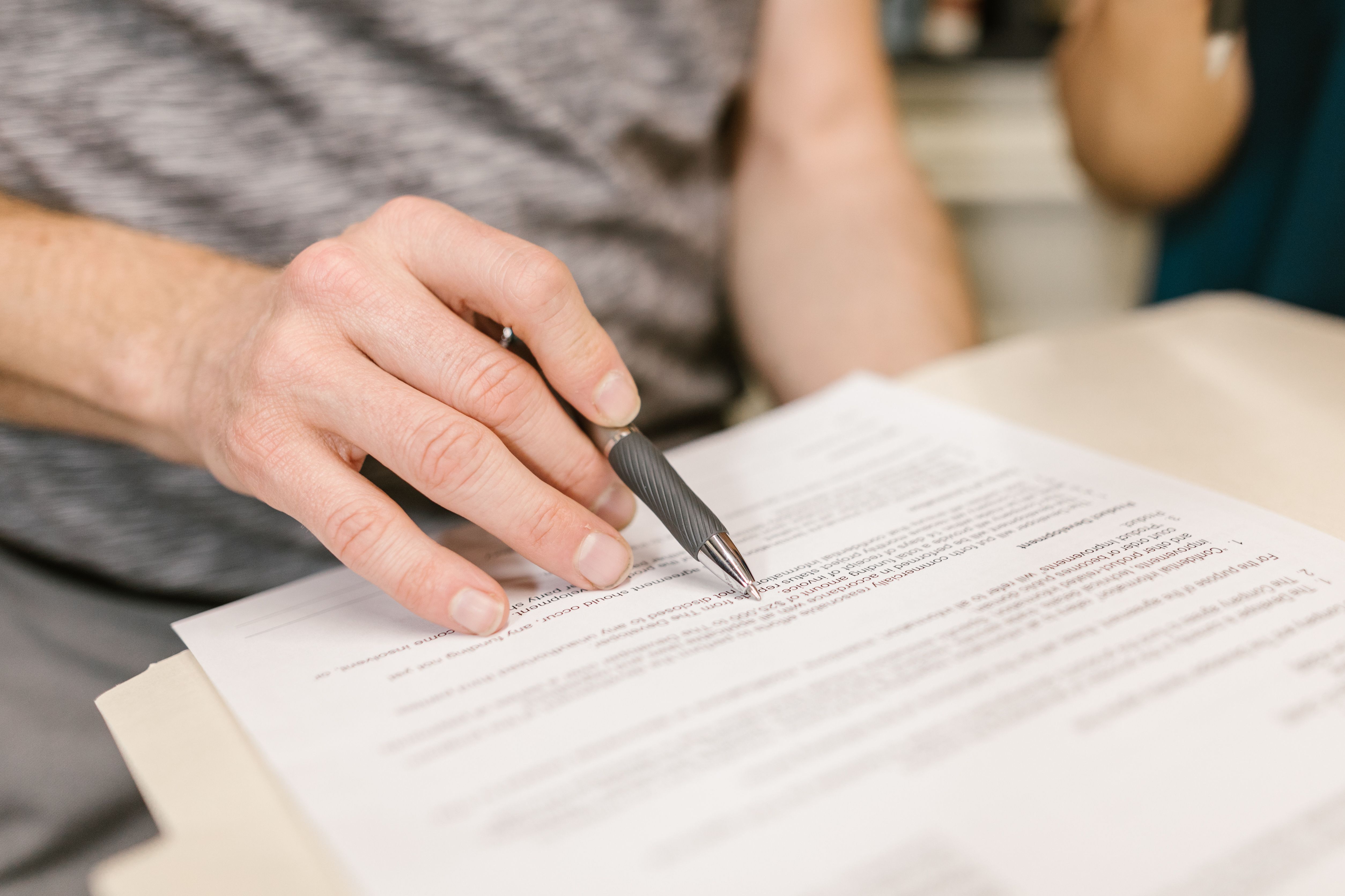 Close-up of a hand signing a legal document to formalize a change in legal representation